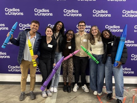 Residents in from of a Crades to Crayons banner holing giant crayons