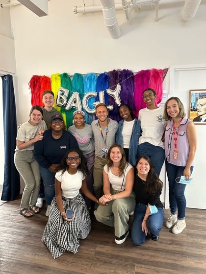 Residents at BAGLY (the name pictured), a community organizations pictured in front of a rainbow banner.