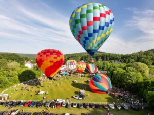 Hot air balloons over Quechee VT at the Quechee Balloon Festival, in a field over parked cars